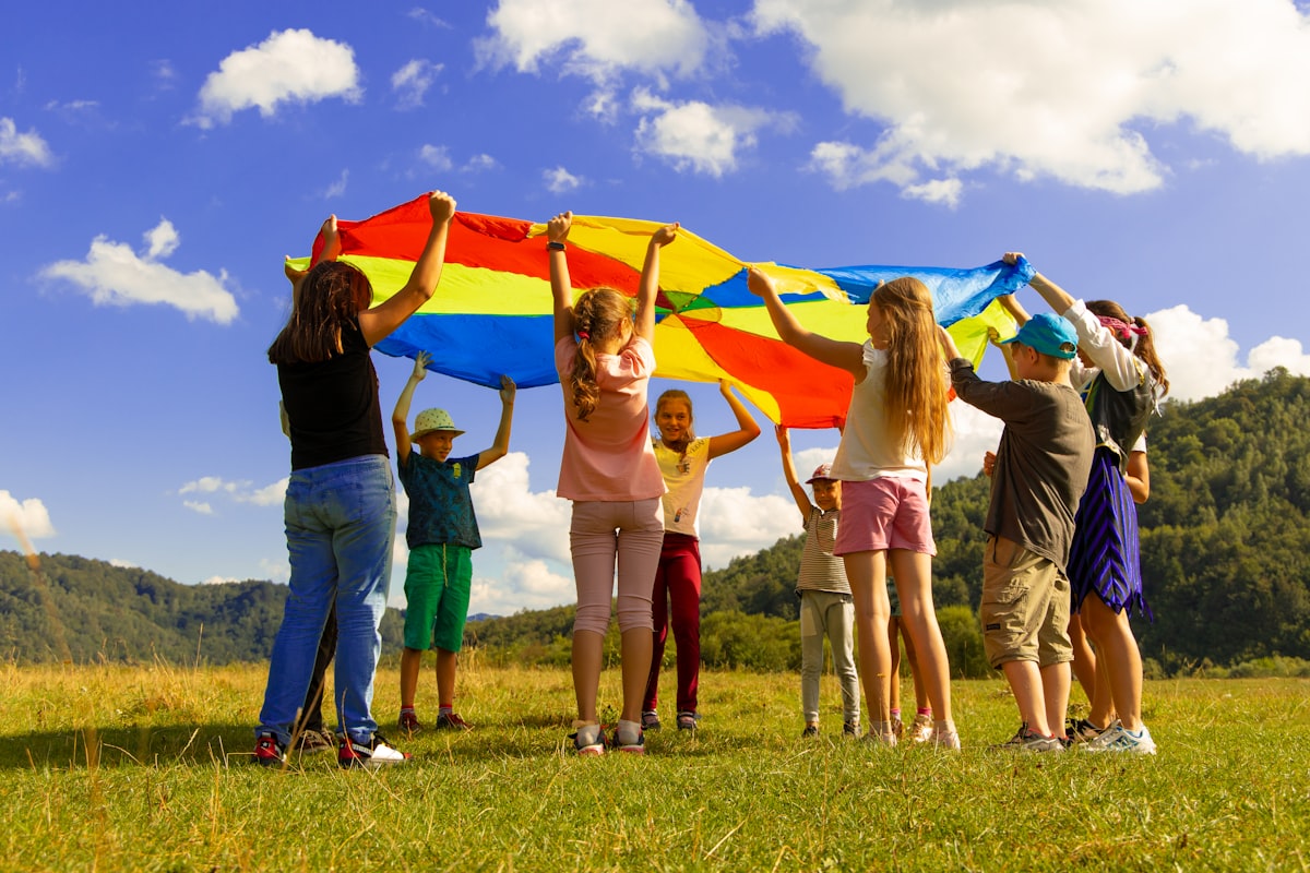 Children playing outdoors with a colourful parachute